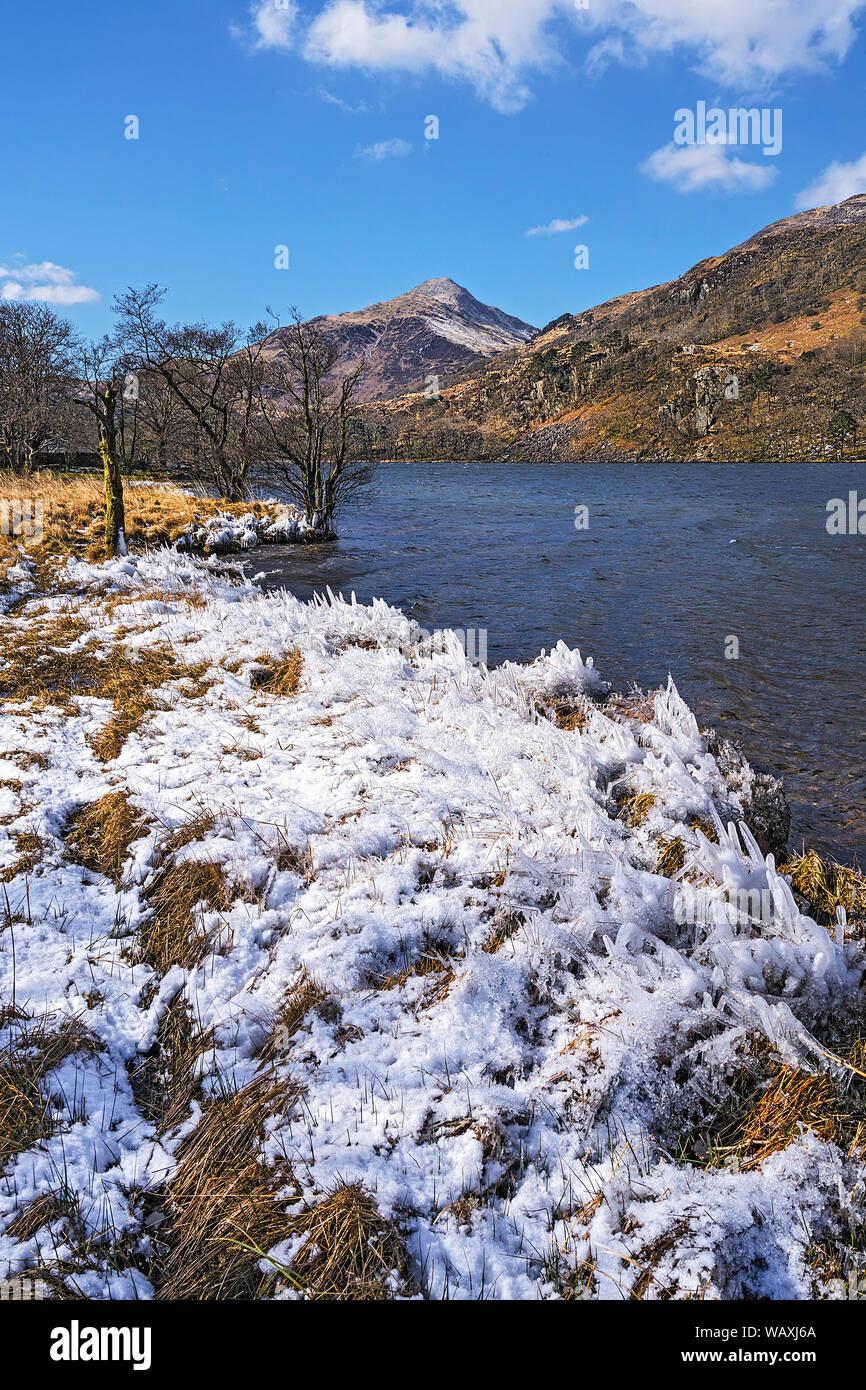 Ice formations on the banks of Llyn Gwynant looking west with Yr Aran mountain in the background Snowdonia National Park North Wales UK March 2018 869 Stock Photo