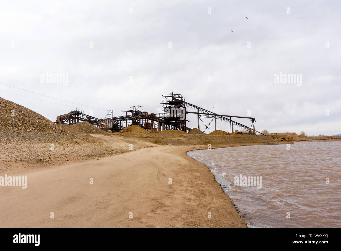 stationary rusty separator of sand and gravel on the sandy bank of the river Stock Photo