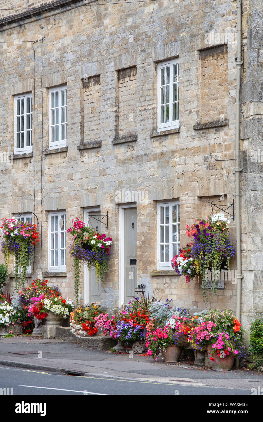 Floral hanging baskets and flower planters outside the Tontine Buildings along Cecily hill, Cirencester, Cotswolds, Gloucestershire, England Stock Photo