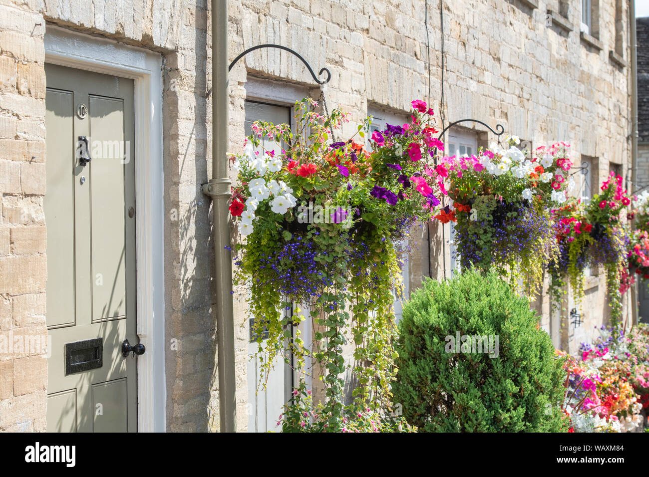 Floral hanging baskets and flower planters outside the Tontine Buildings along Cecily hill, Cirencester, Cotswolds, Gloucestershire, England Stock Photo