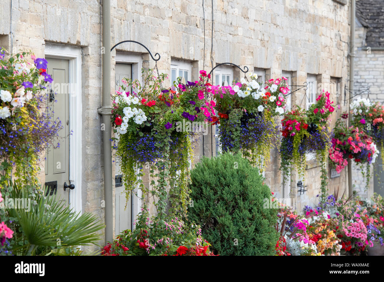 Floral hanging baskets and flower planters outside the Tontine Buildings along Cecily hill, Cirencester, Cotswolds, Gloucestershire, England Stock Photo