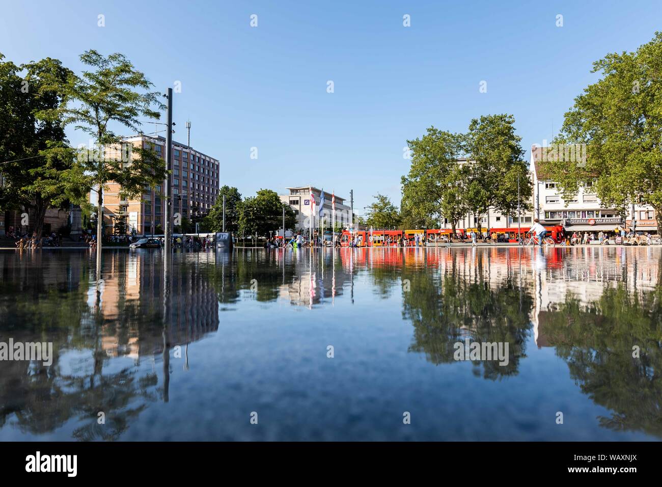 Freiburg, Germany. 22nd Aug, 2019. Passers-by and a tram are reflected ...