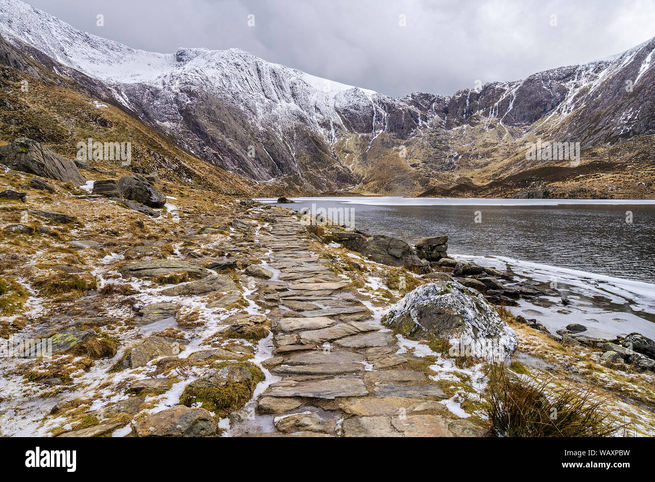 Footpath alongside Llyn Idwal towards the cliffs below Glyder Fawr and the Devils Kitchen Snowdonia National Park North Wales UK March 2018 Stock Photo