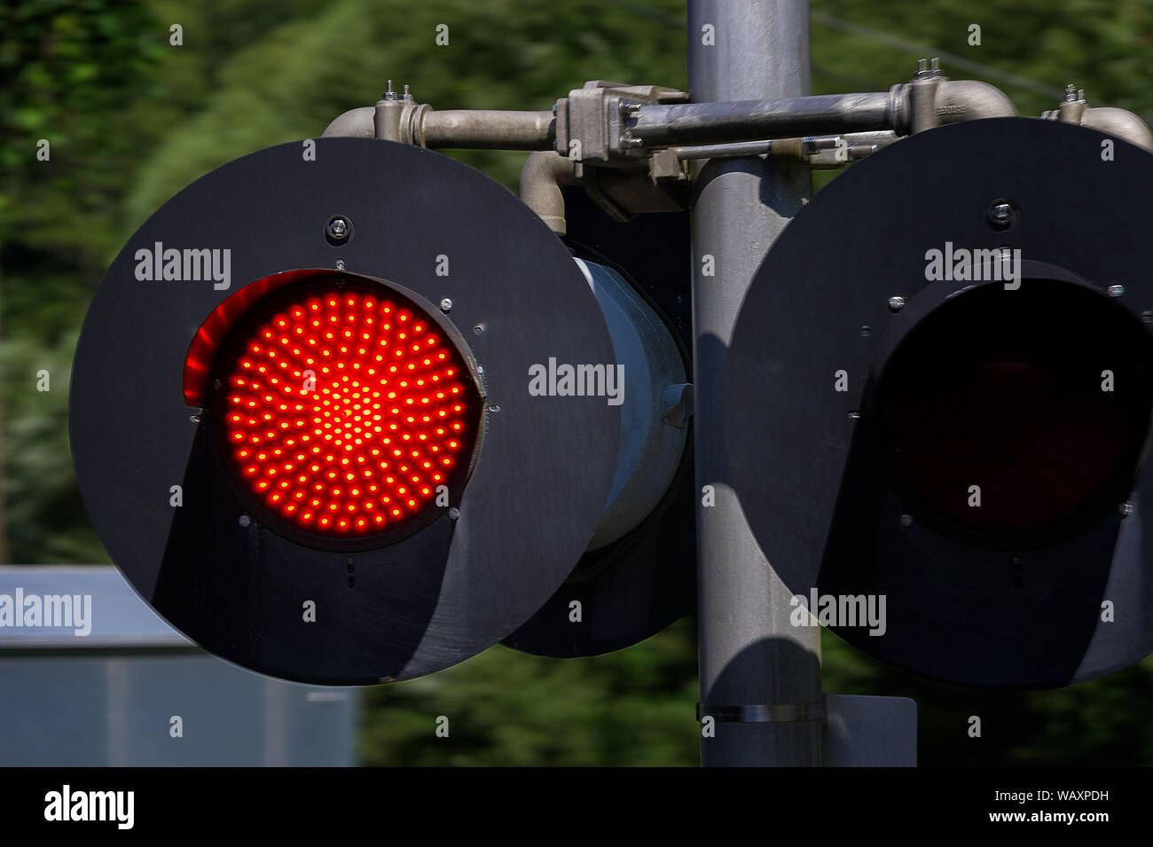 Close up of a red railroad crossing traffic light seen from a moving