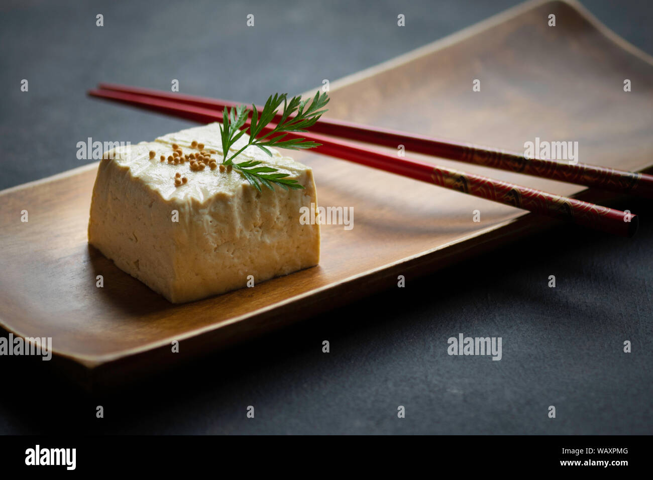 block of tofu in close-up view on wooden plate and chopsticks Stock Photo