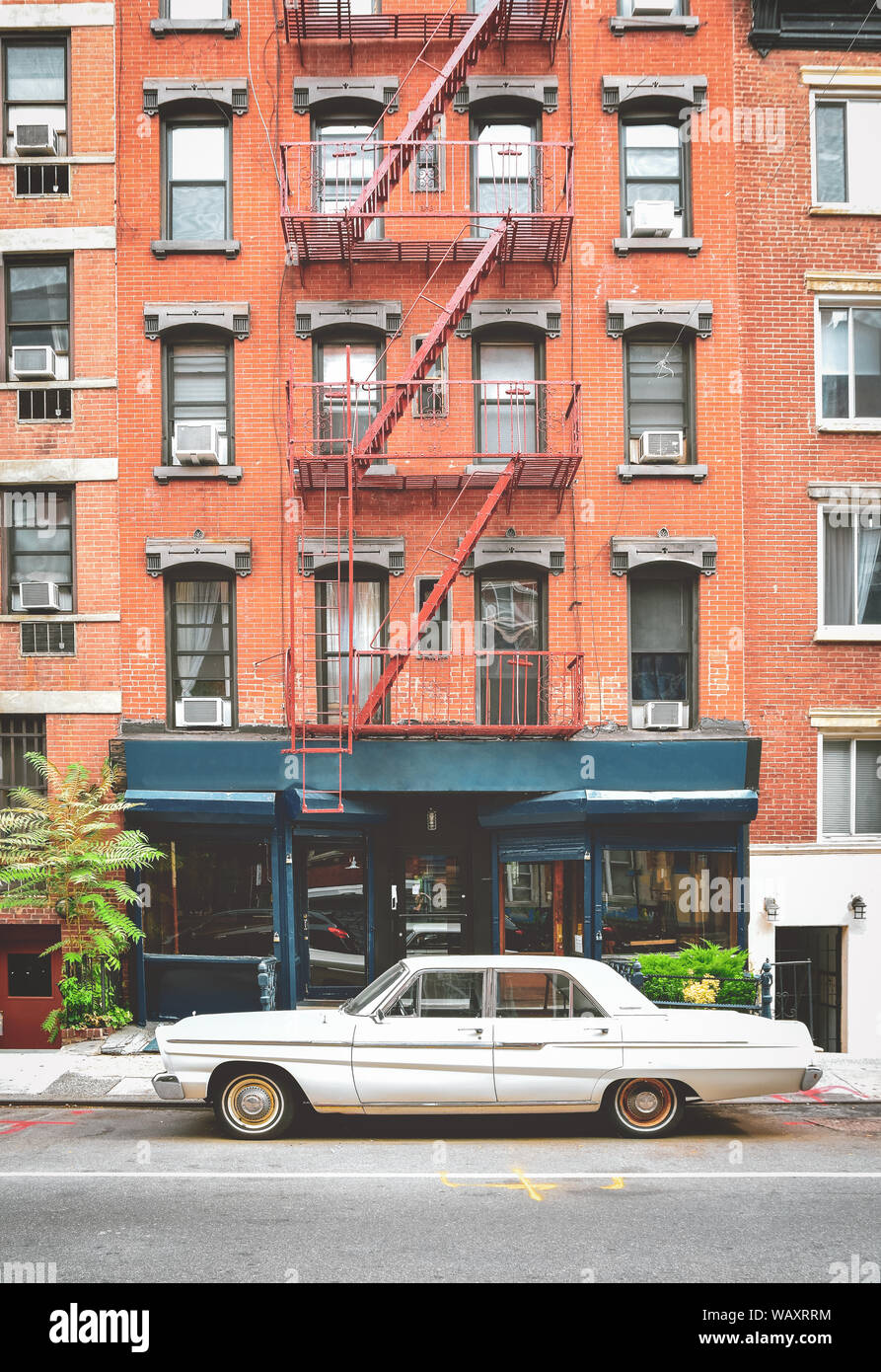 Typical red brick buildings with fire stairs in NYC. Classic car in the foreground and vintage photo effect. Stock Photo