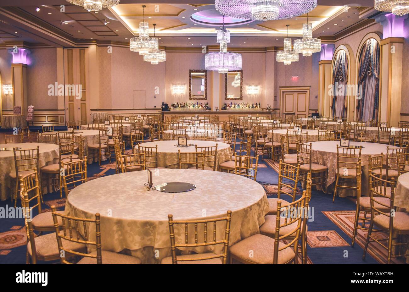 A Wide Shot Of Gold Chairs Around Tables In A Wedding Hall With