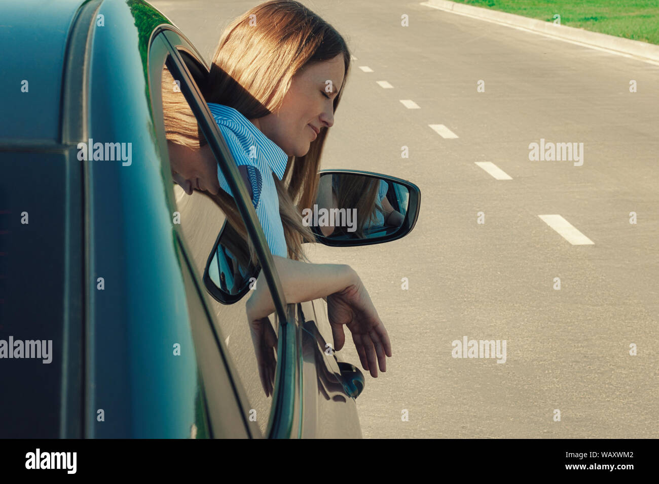 A woman looks out the window of the car. There's a road in the ...