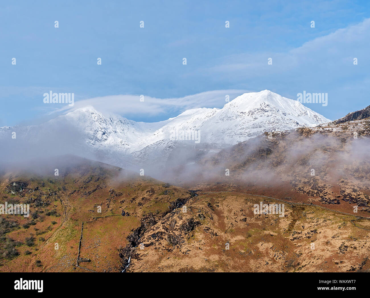 The summits of Mount Snowdon left and Crib Goch right wreathed in mist Snowdonia National park North Wales UK March 7647 Stock Photo