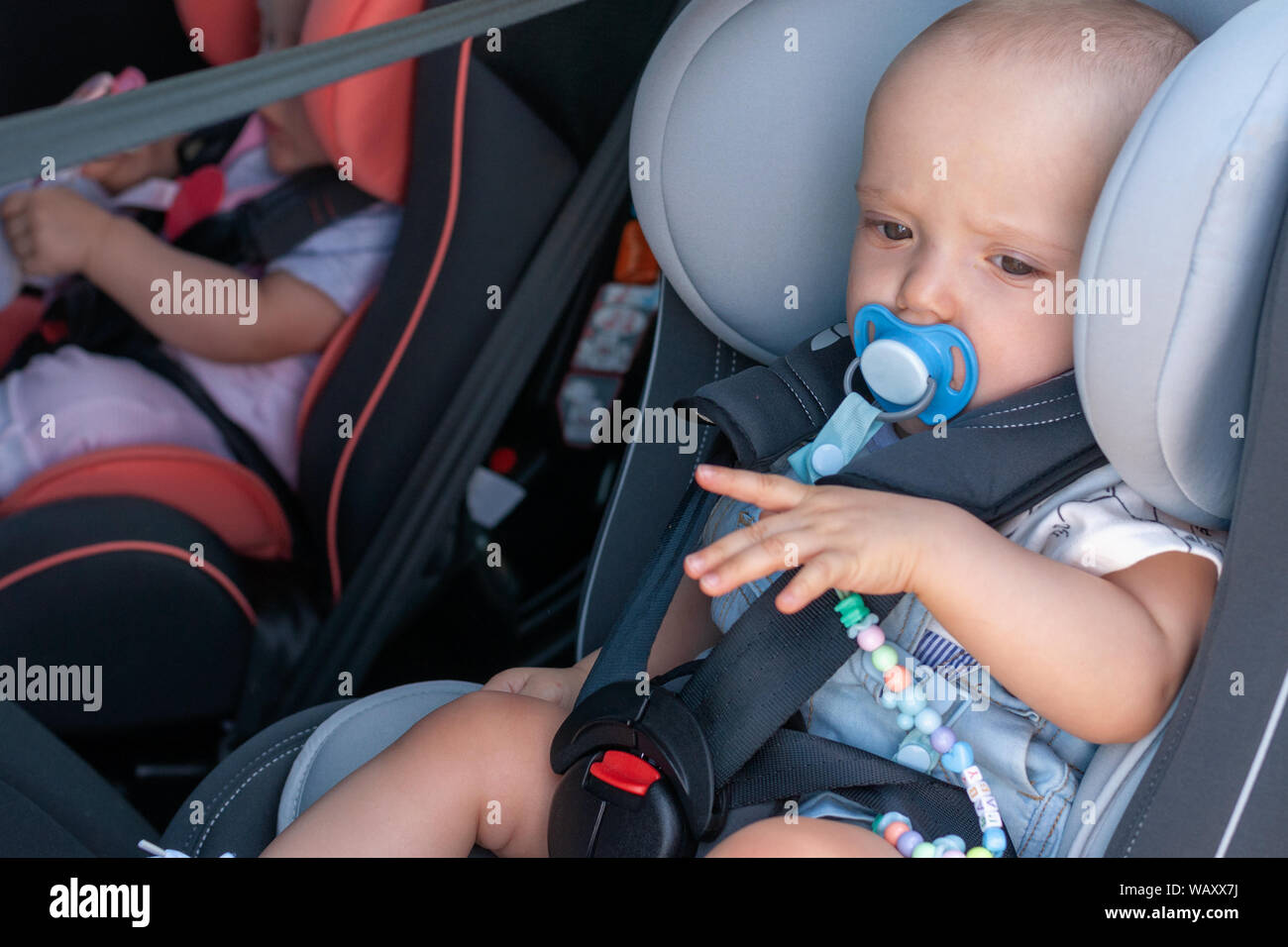 Twins boy and girl in child seats in the car. Safety transportation for babies. Children up to a