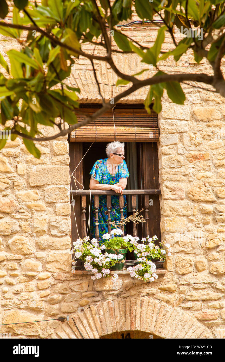 Woman standing looking out from a small balcony in a Spanish stone built house in the village of Puente La Reina Navarre /  Navarra Spain Stock Photo