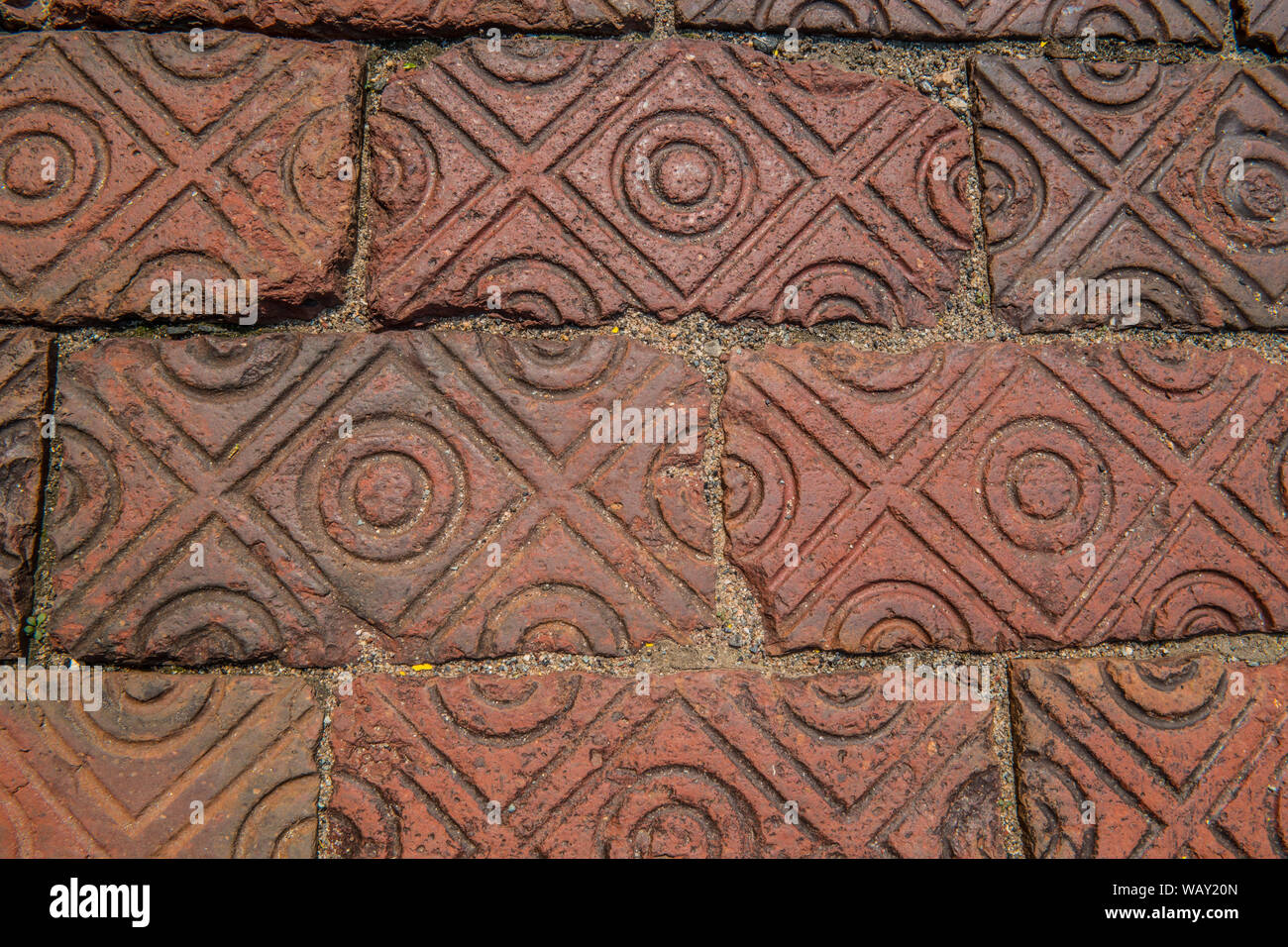 Old vintage red clay brick sidewalk with unique patterns stamped in Stock Photo
