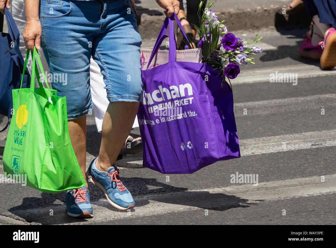 Bucharest, Romania - August 13, 2019: People carrying shopping bags cross a street in Bucharest. Stock Photo