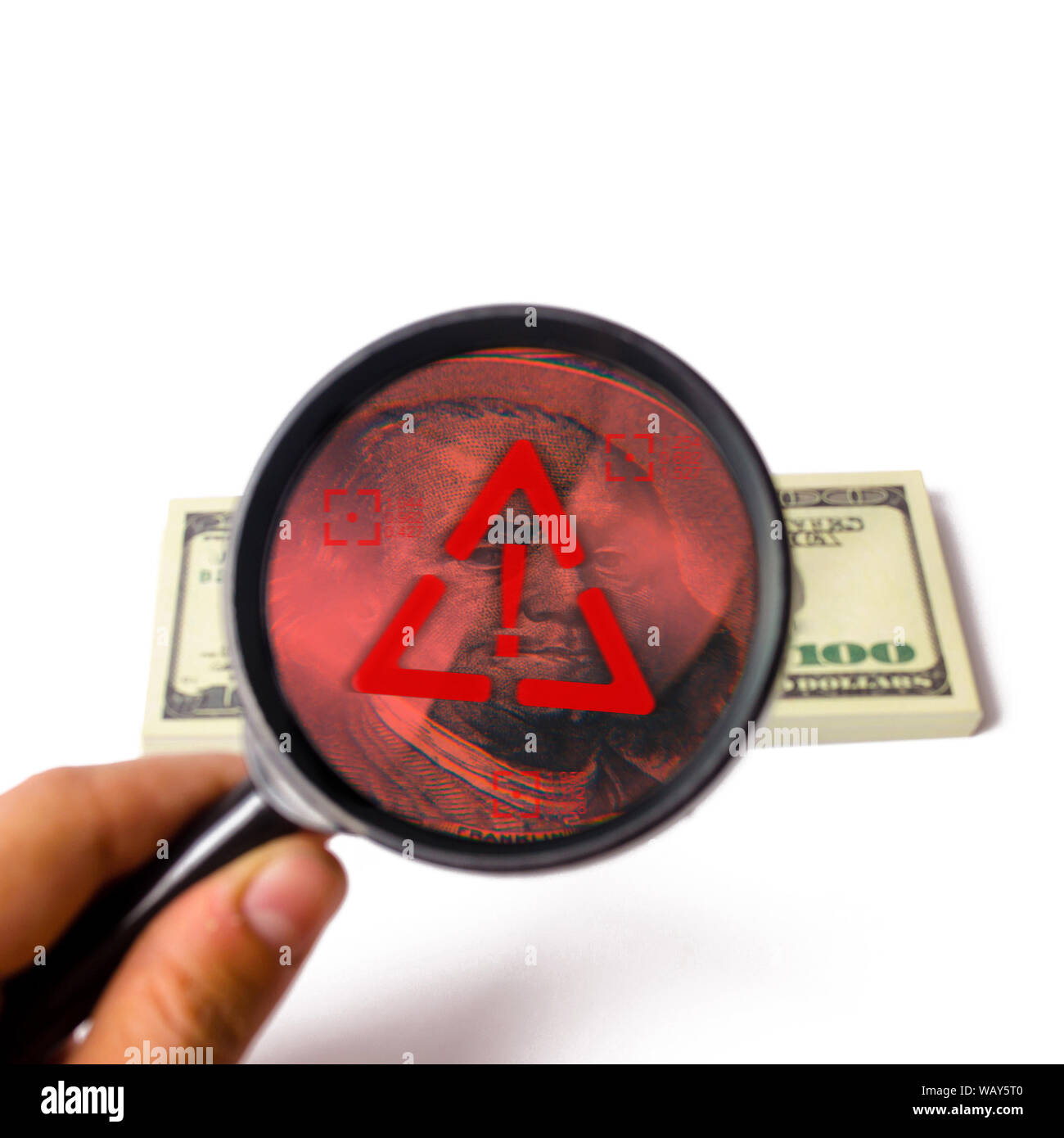The hand holds a magnifying glass and looks bundle of dollars. Fake ...