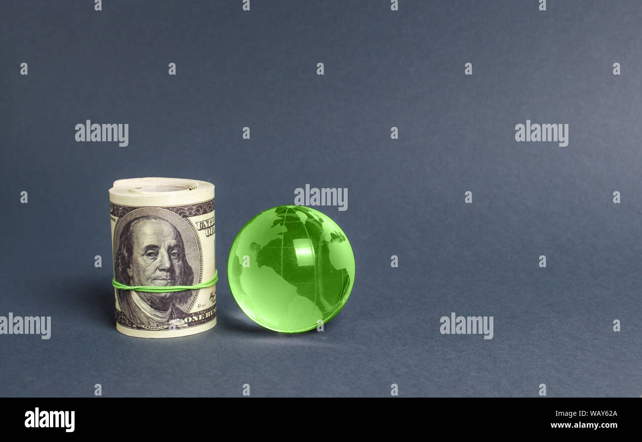 Roll of dollars and green planet earth globe. International money transfers, attraction of investments. Global financial system. World trade and econo Stock Photo