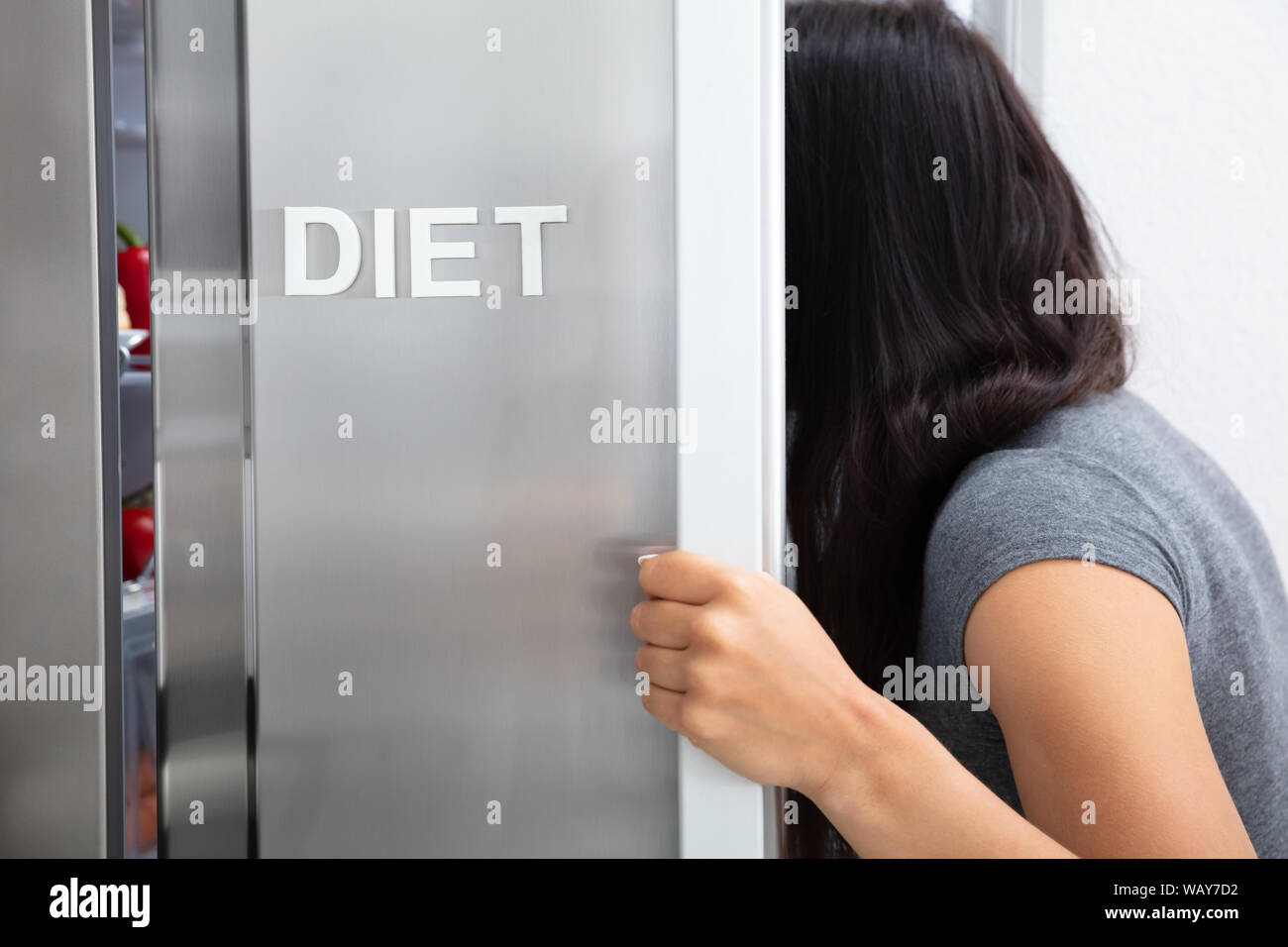 Close-up Of Woman Searching Diet Food In Opened Refrigerator Stock Photo