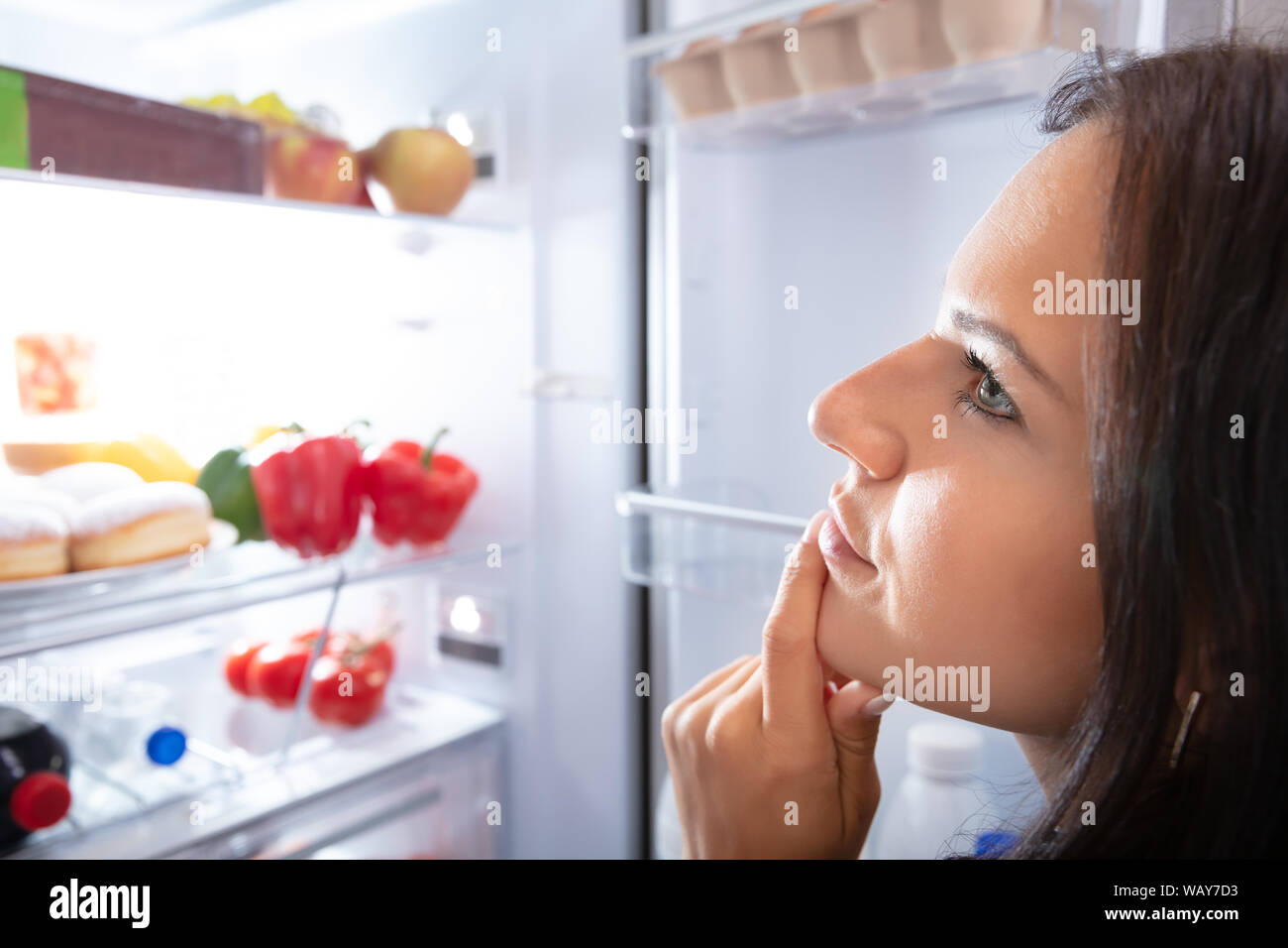 Pretty Woman Looking For Food In Refrigerator Stock Photo