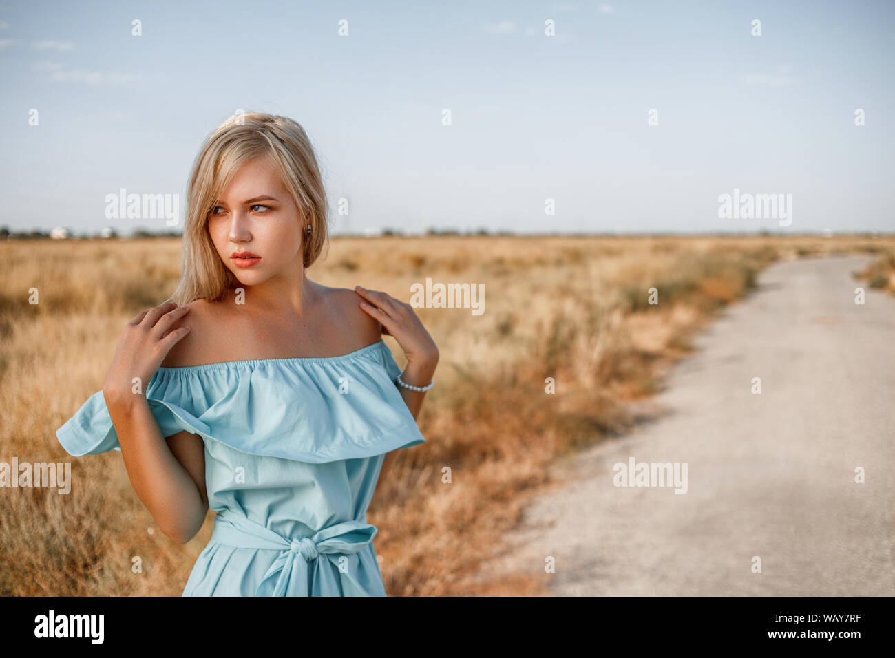 portrait of a young beautiful caucasian blonde girl in a light blue ...