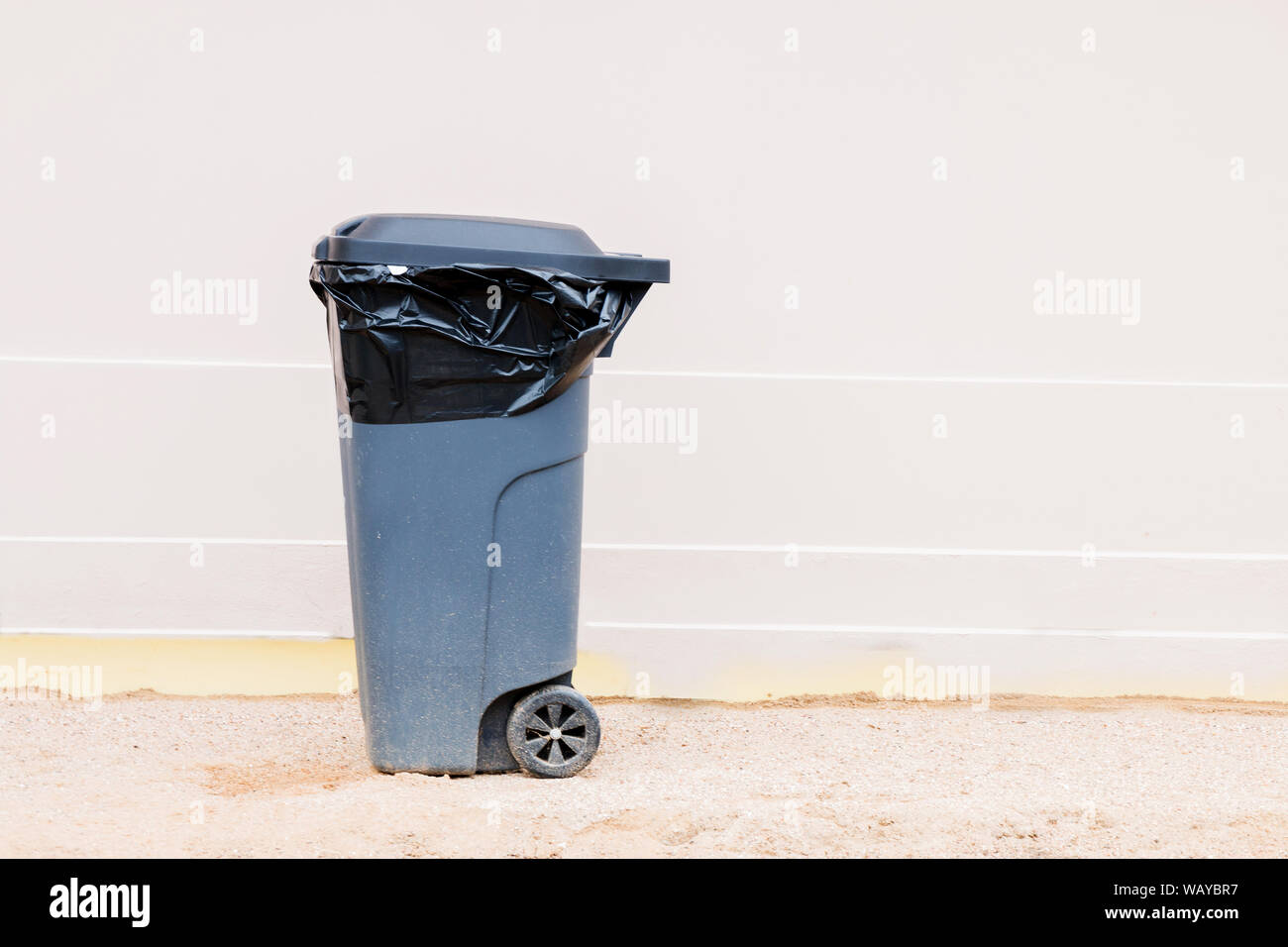 Gray garbage container with garbage bag isolated on light background, trash can. Stock Photo