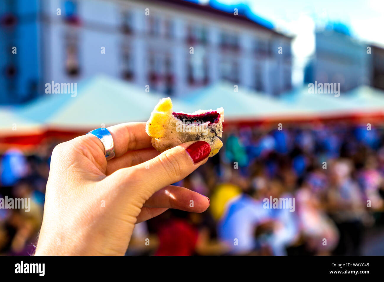 Hand holding a traditional Polish fried blueberry dumpling at the 16th Pierogi Festival in Maly Rynek, Krakow, Poland Stock Photo