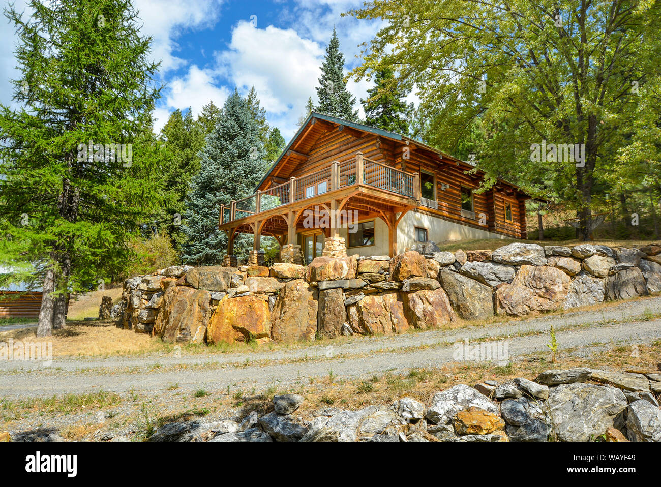 A picturesque rustic log home in the mountains surrounded by pine trees on a rocky hillside in Coeur d'Alene, Idaho. Stock Photo