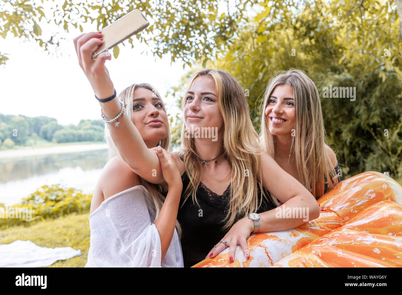 female millennial girlfriends taking a selfie outdoors on the river. youth summer vacation concept Stock Photo