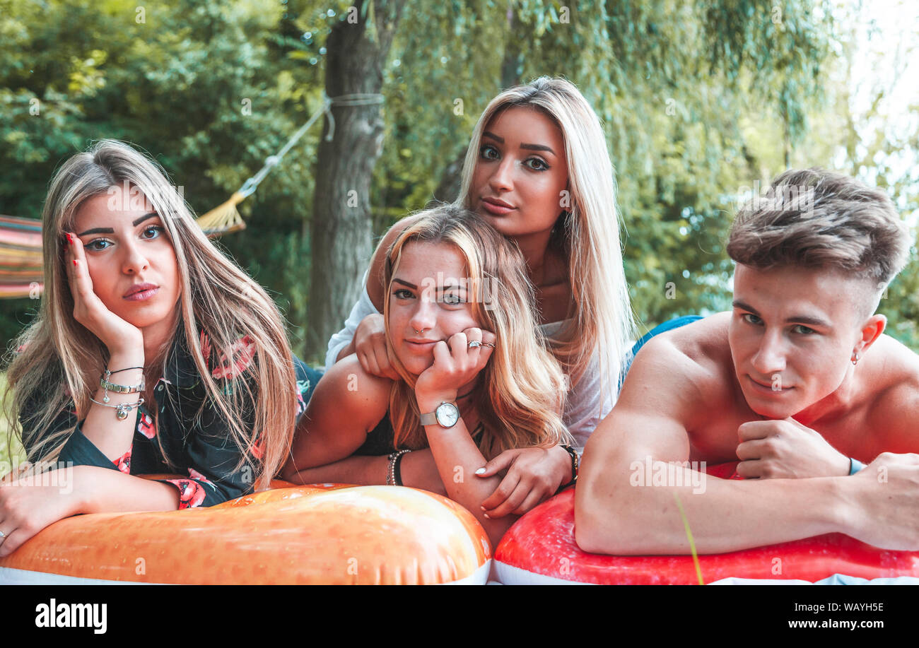 portrait millennial group of friends lying in the grass outdoors on the river. youth summer vacation concept Stock Photo
