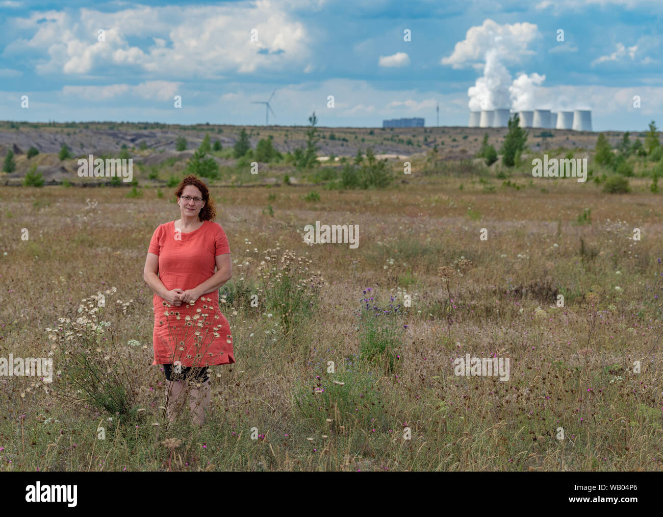 13 August 2019, Brandenburg, Jänschwalde: Christina Grätz, graduate biologist and managing director of Nagola Re GmbH, is standing on a recultivation site in the Jänschwalde lignite opencast mine of Lausitz Energie Bergbau AG (LEAG). The Jänschwalde lignite-fired power plant can be seen in the background. Saxony and Brandenburg are on the verge of state elections. A mood report from the two federal states (to dpa-story: Landtag elections - old wounds, new fears) Photo: Patrick Pleul/dpa-Zentralbild/dpa Stock Photo