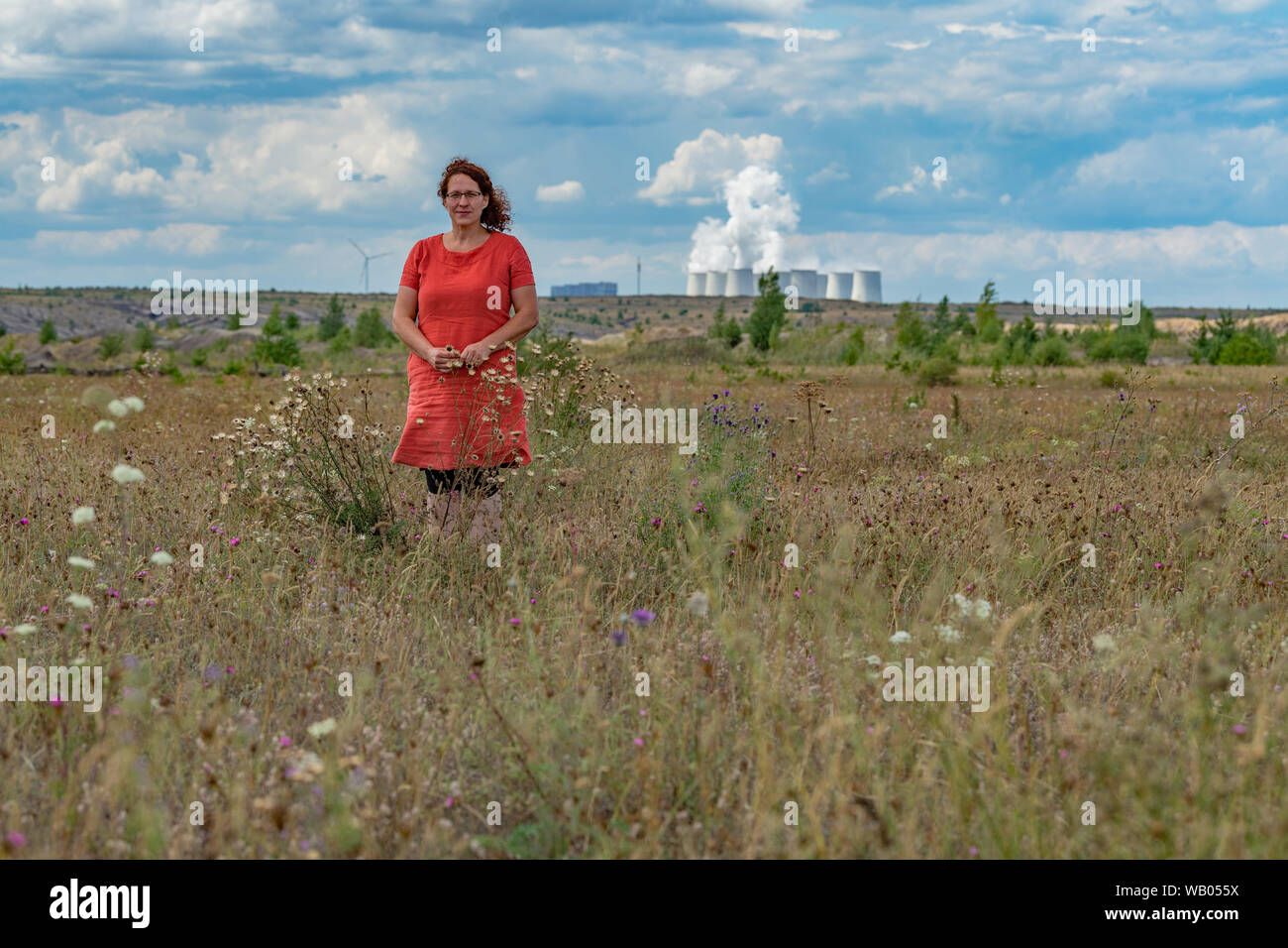 13 August 2019, Brandenburg, Jänschwalde: Christina Grätz, graduate biologist and managing director of Nagola Re GmbH, is standing on a recultivation site in the Jänschwalde lignite opencast mine of Lausitz Energie Bergbau AG (LEAG). The Jänschwalde lignite-fired power plant can be seen in the background. Saxony and Brandenburg are on the verge of state elections. A mood report from the two federal states (to dpa-story: Landtag elections - old wounds, new fears) Photo: Patrick Pleul/dpa-Zentralbild/dpa Stock Photo