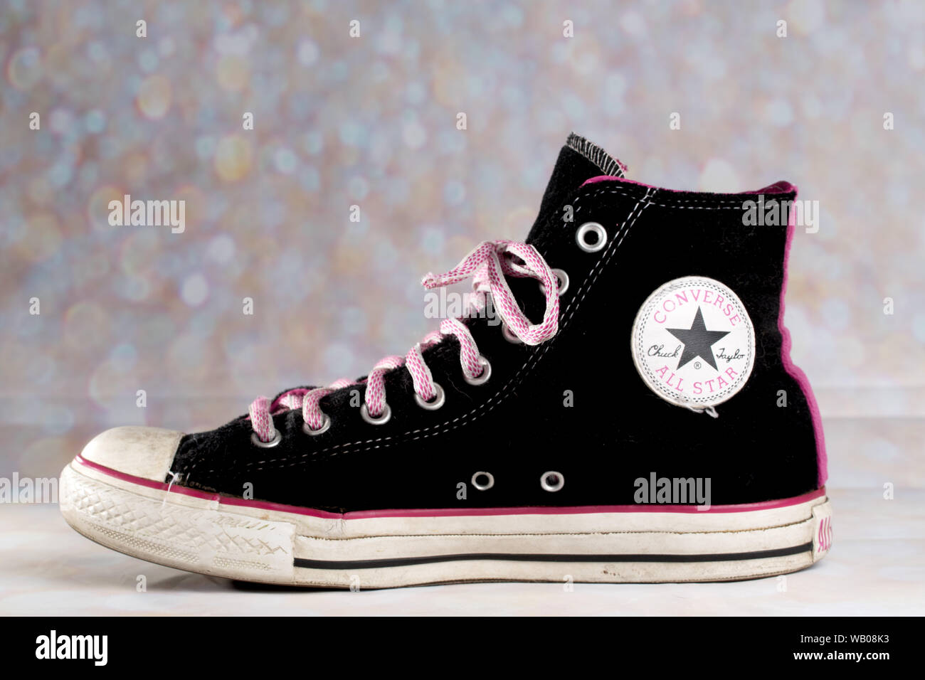 Pink and Black Converse Sneaker worn against a blurry background has pink  shoelaces Stock Photo - Alamy