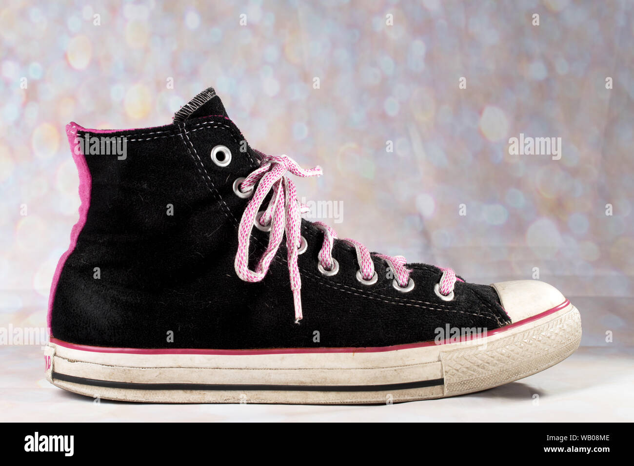 Pink and Black Converse Sneaker worn against a blurry background has pink  shoelaces Stock Photo - Alamy