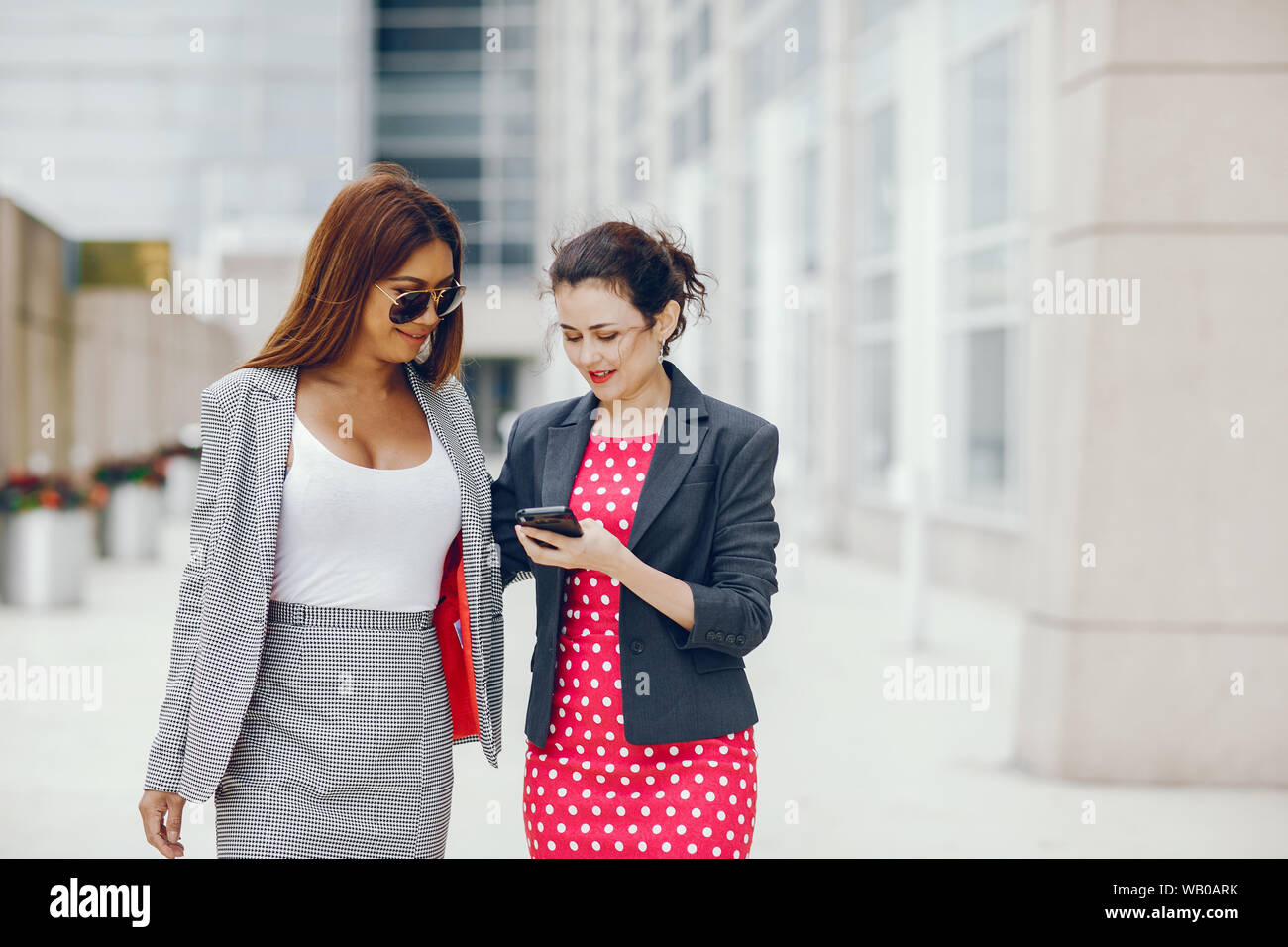 Beautiful businesswomen in a city. Businesswomen in a elegant dress. Ladies  in a city. Pretty girls with phone. Two partners in a fashoin clothes Stock  Photo - Alamy