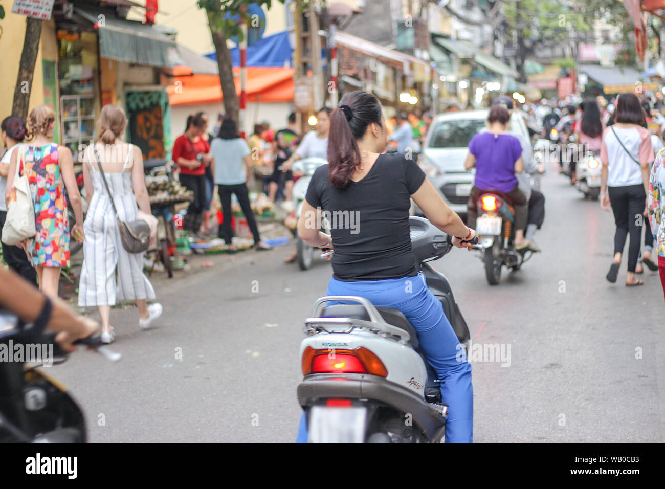 A woman is riding on motorbikes in Hanoi, Vietnam. Stock Photo