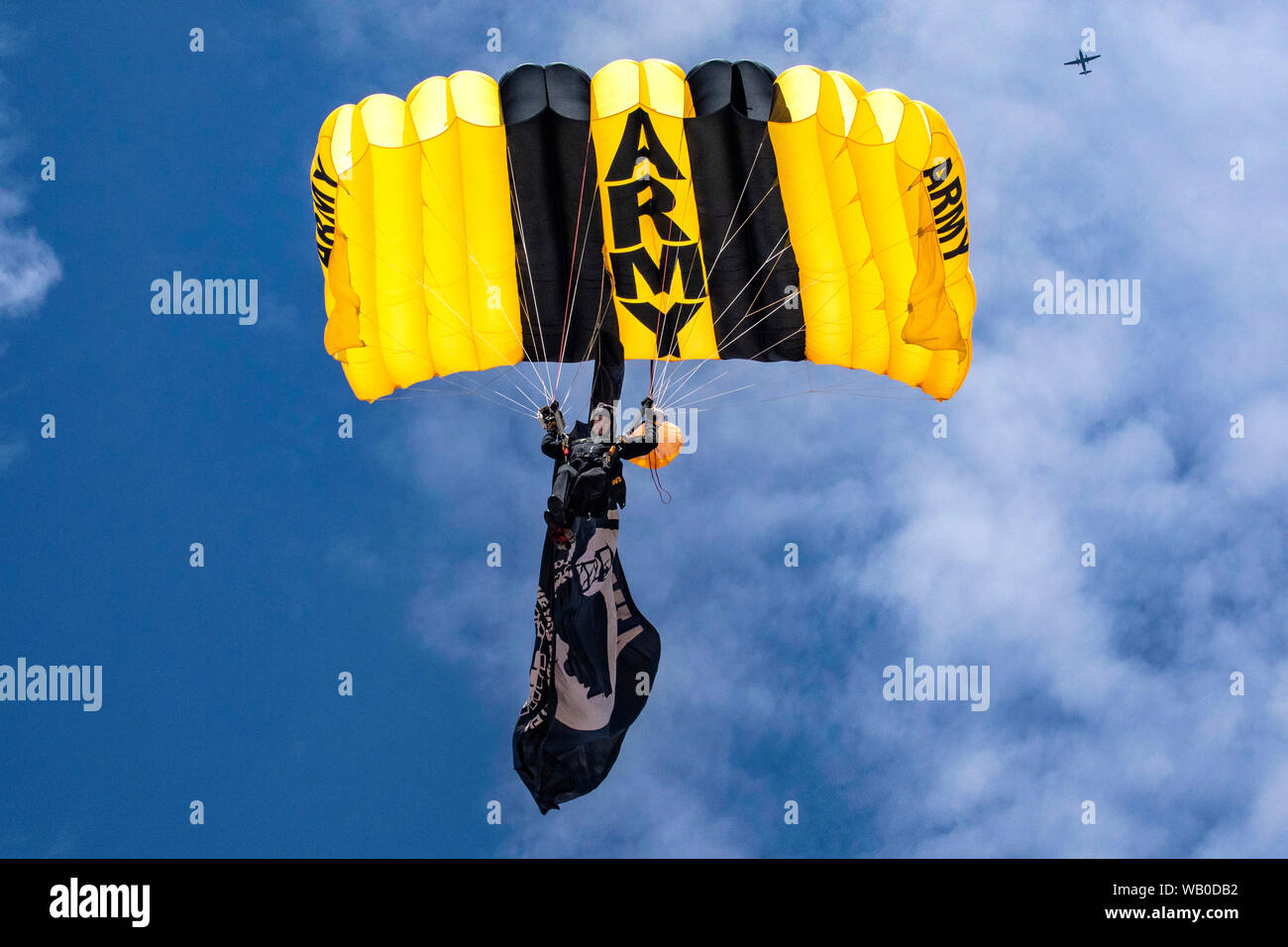 A U.S. Army Soldier with the U.S. Army Golden Knights Parachute Team prepares to land at show center while a C-31A Troopship orbits above during the 2019 Atlantic City International Airshow “A Salute To Those That Serve” at Atlantic City, N.J., Aug. 21, 2019. (New Jersey National Guard photo by Mark C. Olsen) Stock Photo
