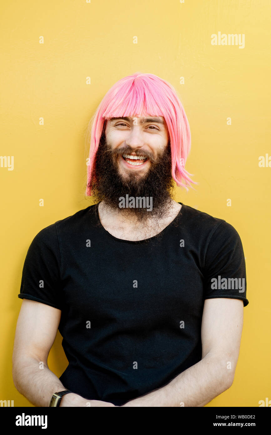 Funny portrait of a stylish playful man with beard and long color hair with  expressive emotions on the yellow background Stock Photo - Alamy