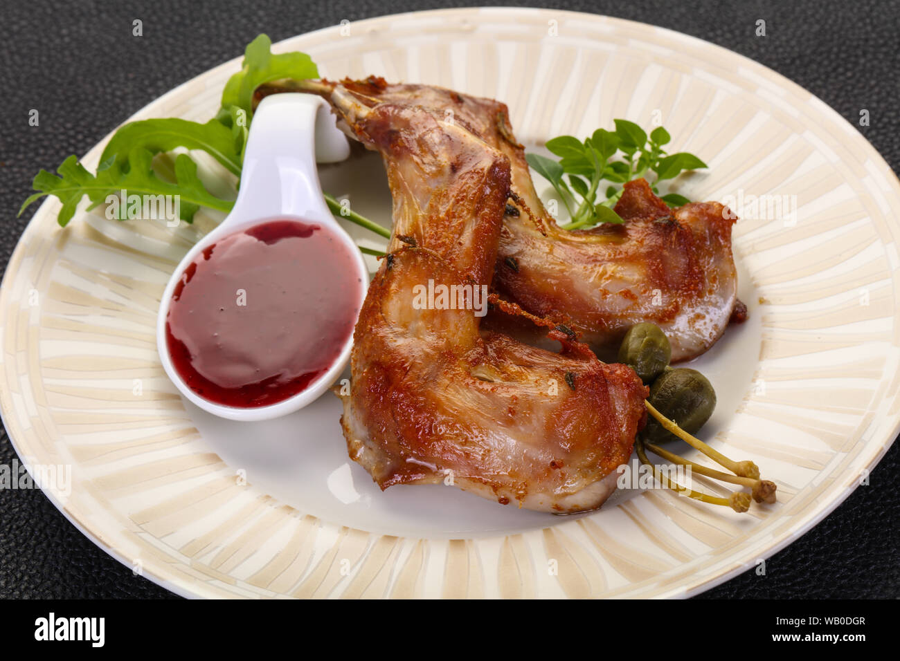 Roasted rabbit legs with cowberry sauce Stock Photo - Alamy