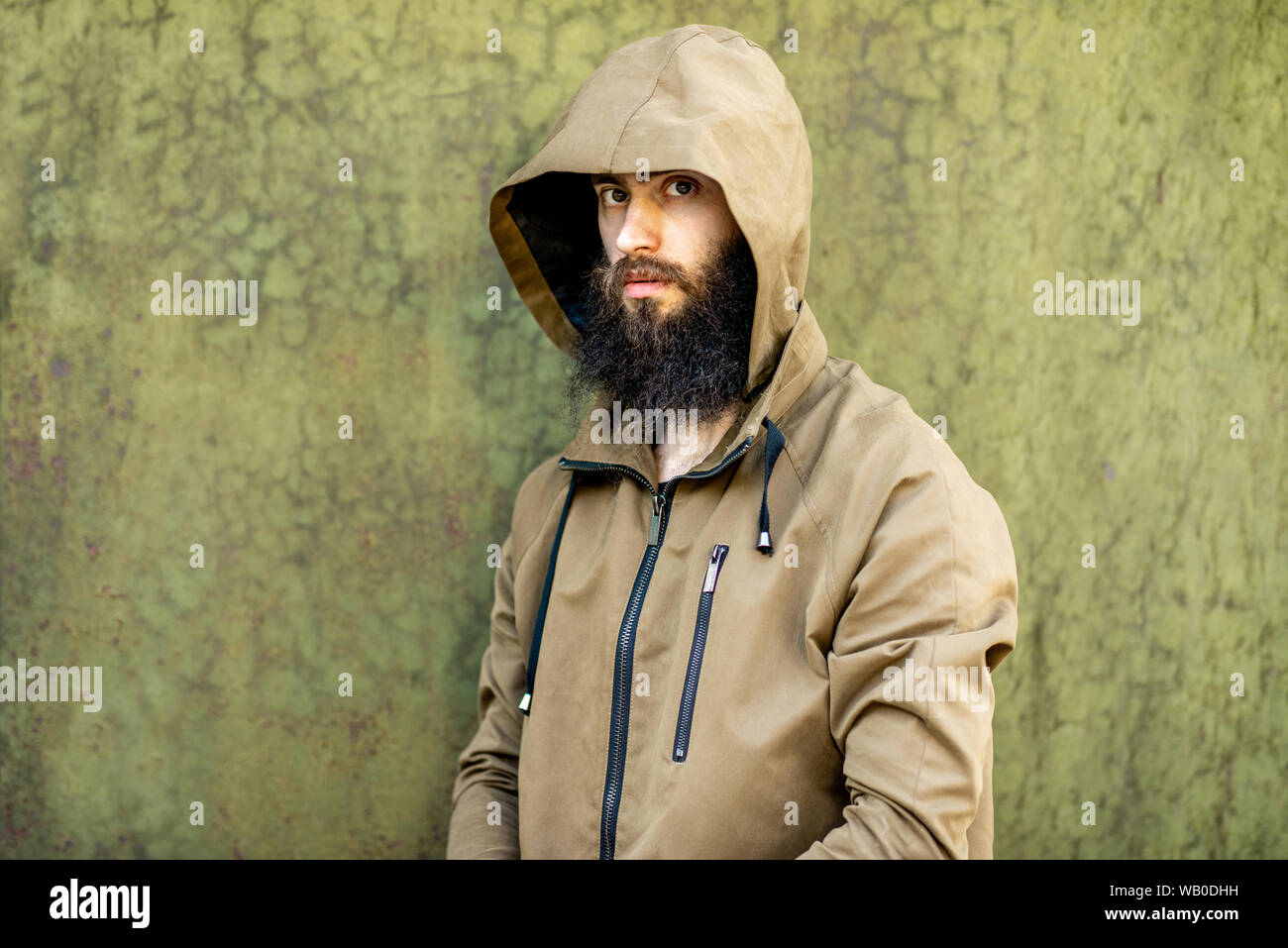 Portrait of a mysterious and weird man wearing hoodie coat on the green  rusty wall background Stock Photo - Alamy