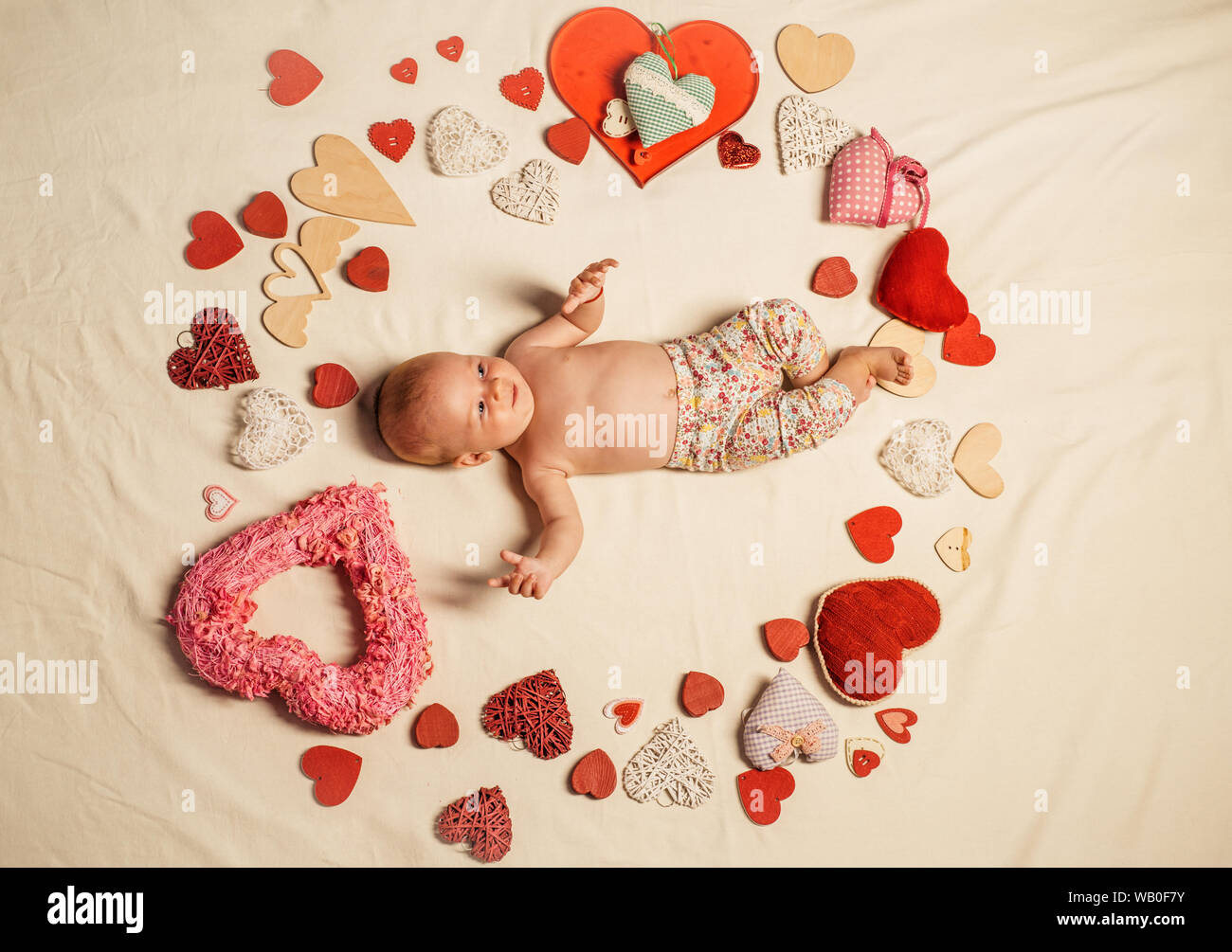 Love. Childhood happiness.Valentines day. Small girl among red hearts. Sweet little baby. New life and birth. Family. Child care. Love and trust Stock Photo