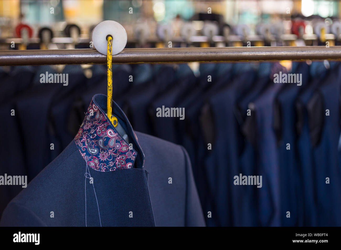 Unfinished suit jackets hanging on assembly line in European garment factory. Fashion production line. Stock Photo