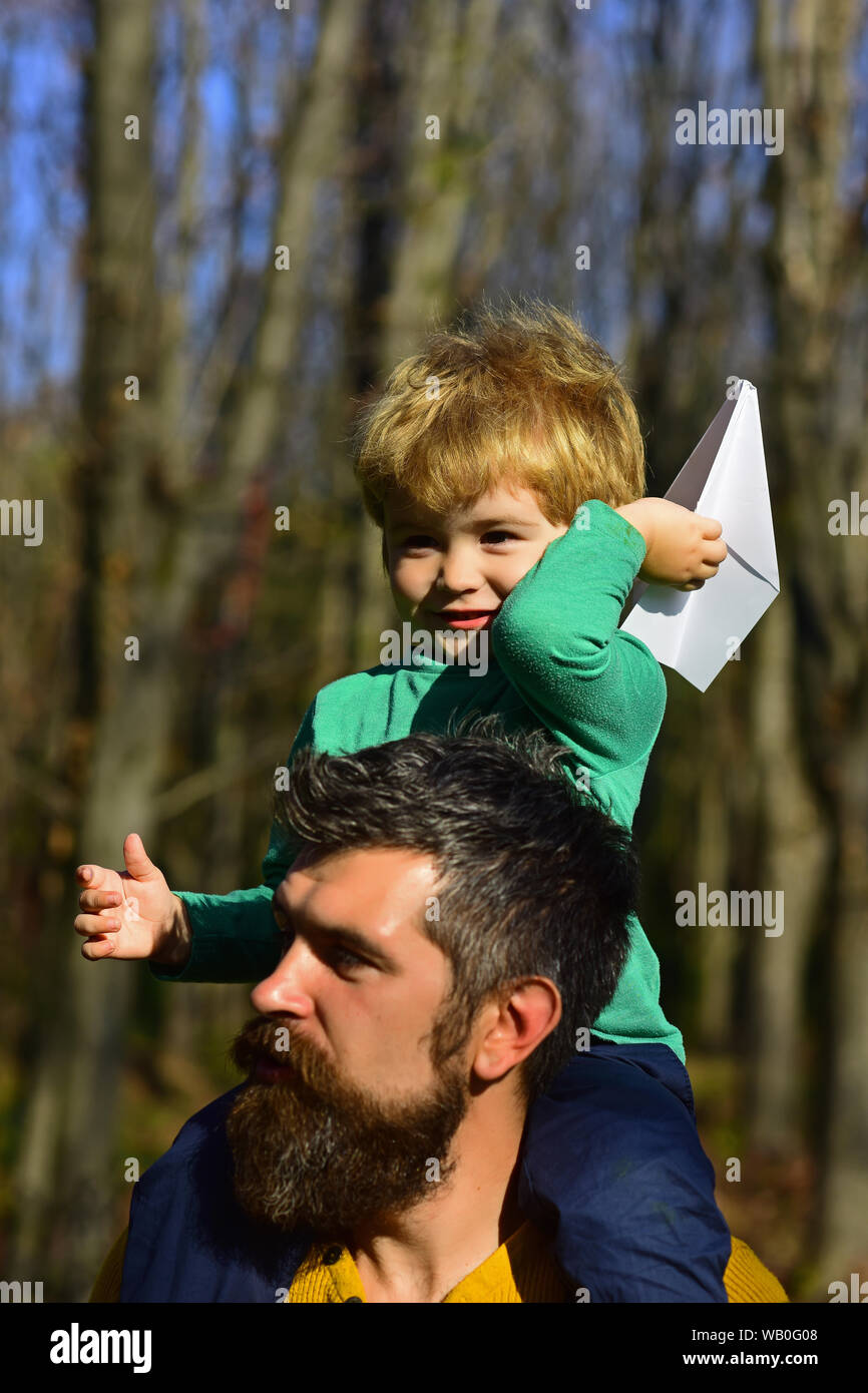 Father and son launch paper plane in park. Father and son play together outdoor. Grab fun with travel Stock Photo