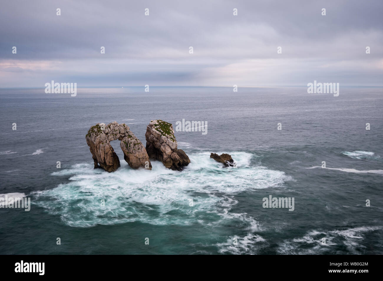 Urros Manzano Bizarre dramatic Rock in raging  waves under cloudy sky at the coast of Cantabria, Northern Spain Stock Photo