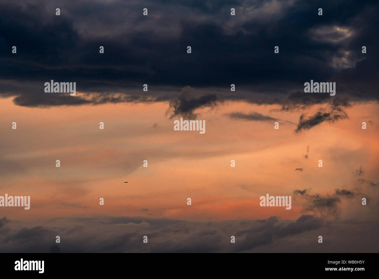 Beautiful sunset sky. Aircraft flying on dark and pastel sky. Art picture of sky at sunrise. Sunrise and fluffy clouds for inspiration background. Stock Photo