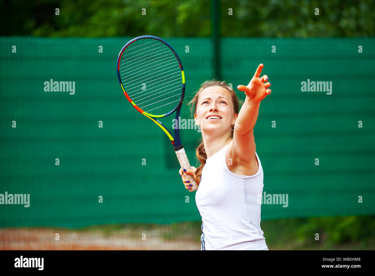 Young beautiful female tennis player serving. Stock Photo