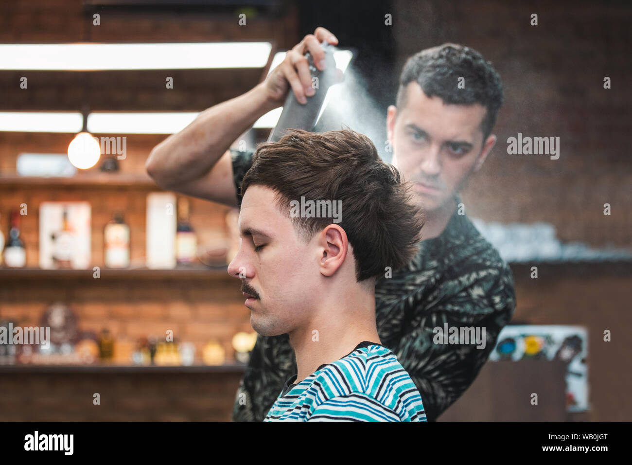 Professional Hairdresser using hair spray on client hair at barber shop,  Cool barber splashes from the spray bottle at the hair of his client Stock  Photo - Alamy