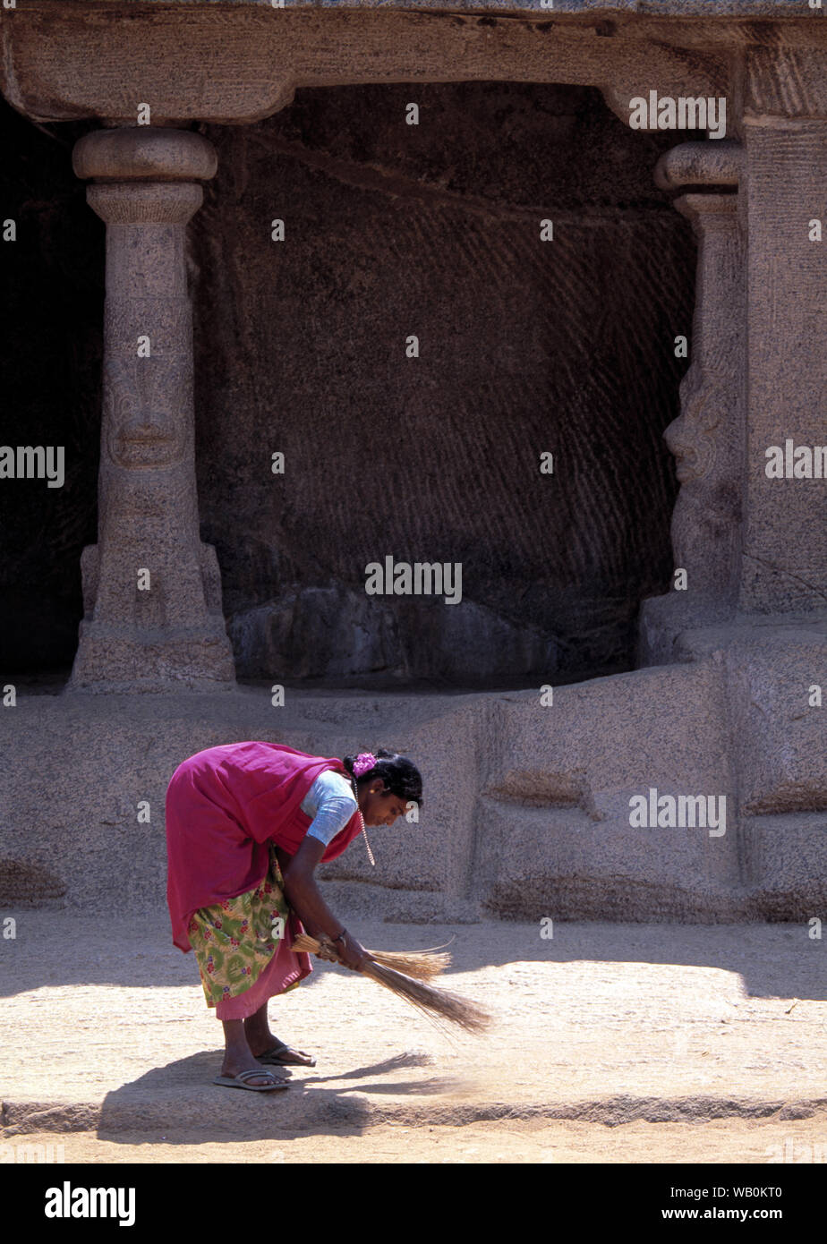 indian women sweeping path in front of religious temple with straw brush Stock Photo