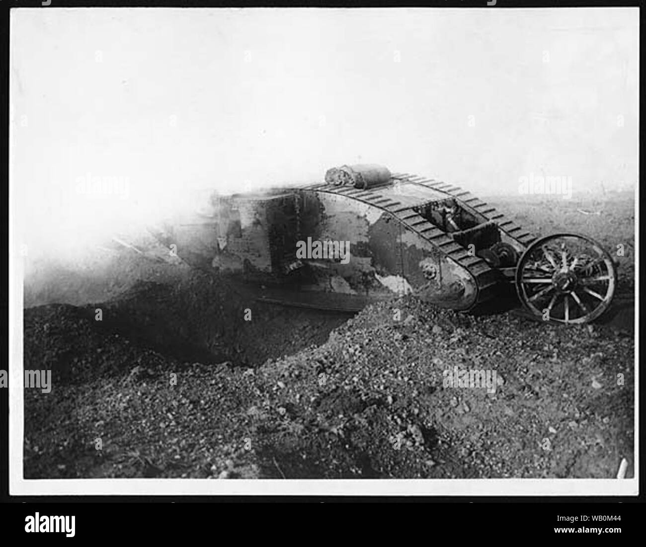 A tank, with guns apparently firing, crossing a trench or shell-hole. The tank appears to be a Mark I type, nicknamed, 'Mother'. These were the first tanks used in action and were developed from a prototype demonstrated in 1915, called 'Little Willie'. They were fitted with a 6-pound (2.7 kilos) naval gun on each side.  The tanks were first used, rather unsuccessfully, at Flers-Coucelette on 15 September 1916. However, Sir Douglas Haig (1861-1928) was sufficiently impressed with their potential to order more tanks to be supplied and as the war continued new tactics were developed which establi Stock Photo