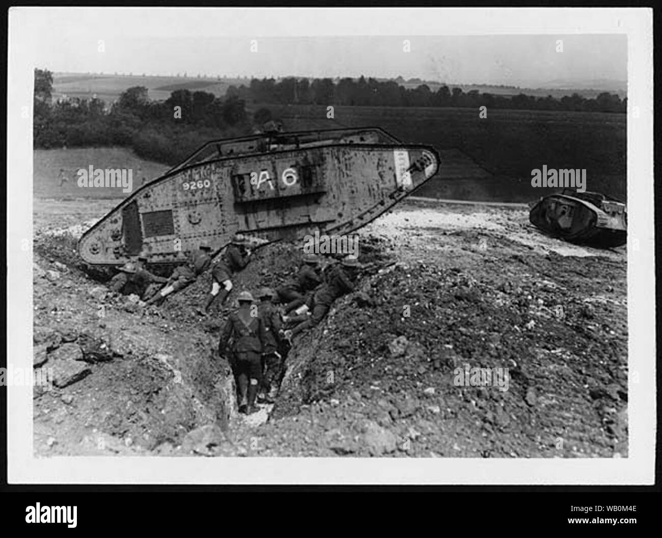 British tanks on training manoeuvres, in France, during World War I. This photograph of an advancing tank dwarfing British troops, gives an idea of the scale of tanks, and the power they brought to the front line in the last years of the war. The earliest models of tank were slow and excessively heavy, and struggled on wet ground, but later models were much more effective.  King George V is not pictured in this photograph, but is known to have visited the Western Front on several occasions. The King was a firm supporter of Haig and instigated his promotion to Field Marshal.  [Original reads: O Stock Photo