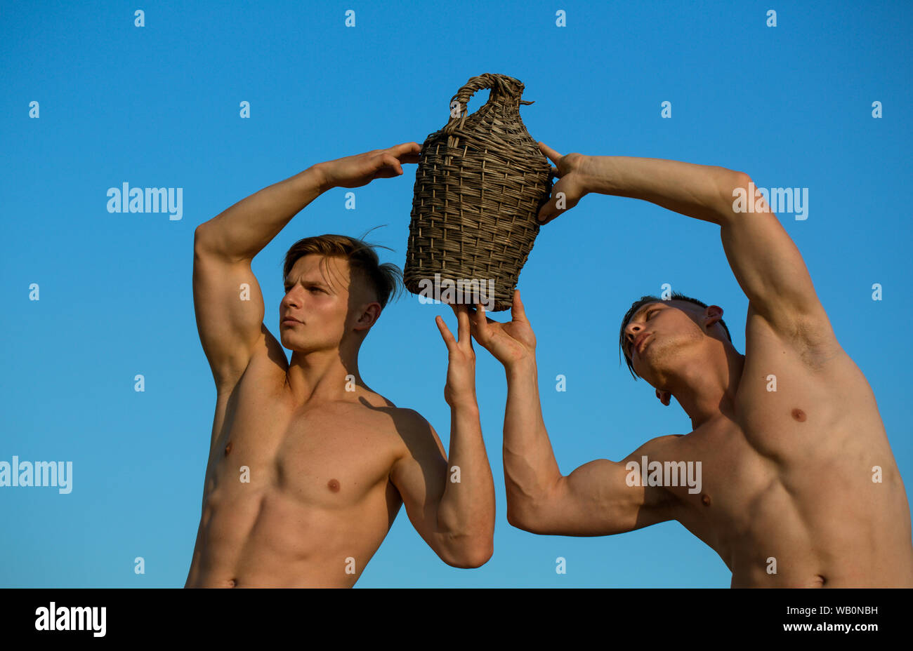 An outstanding vintage. Muscular men hold bottle of wine. Twins brother  with muscular body. Twins men on summer day. Winemaking and wine tasting  Stock Photo - Alamy