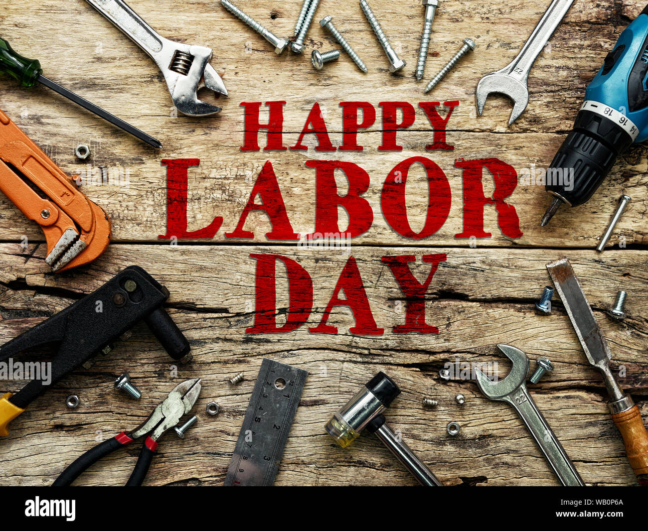 Happy Labor day text in red color on wooden background with construction repair tools. Stock Photo