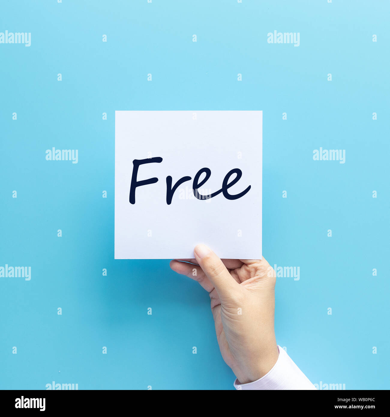 free stuff for advertising concept. hand holding paper with text free isolated on blue background, studio shot Stock Photo